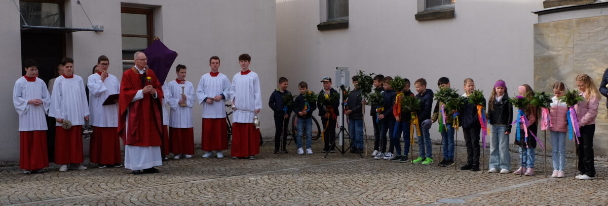 Pfarrer Schemmerer segnet auf dem  Kirchplatz die Palmzweige