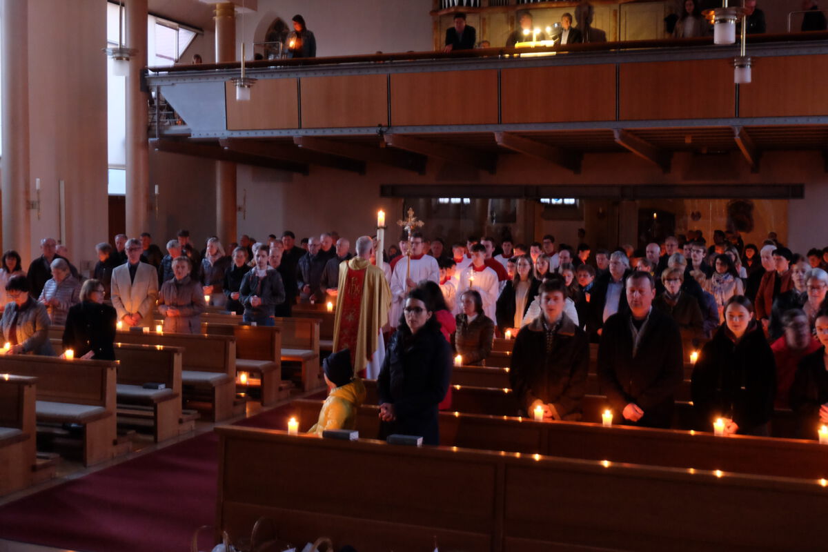 In der noch dunklen Pfarrkirche wird die Osterkerze aufgestellte